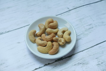 Top view of cashew nuts in bowl on wooden background.