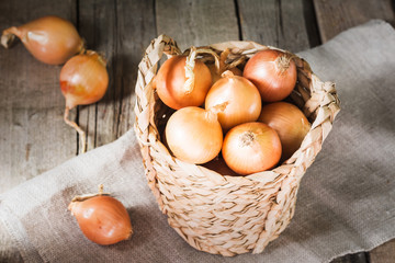 Onion in a basket on a wooden table. Rustic style
