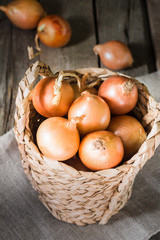 Onion in a basket on a wooden table. Rustic style