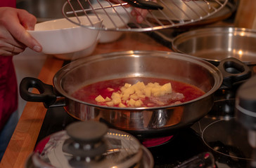 cook preparing lamb soup with vegetables in the kitchen
