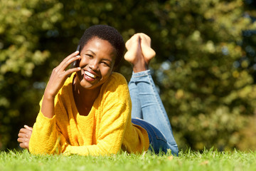 beautiful young black woman lying in park and talking on mobile phone