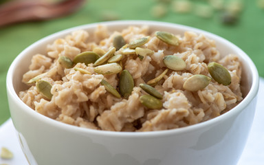 Oatmeal with pumpkin seeds in a white bowl. Healthy breakfast.