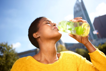 Close up healthy young black woman drinking water outdoors in park