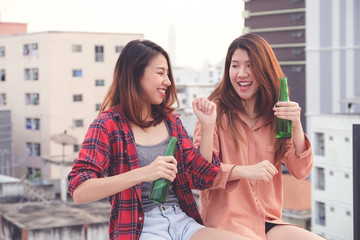 Two asian women drinking at rooftop party, outdoors celebration, friendship, LGBT couple