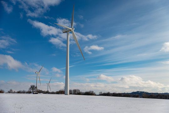 Champ d'éoliennes en hiver sur la neige sur un ciel bleu