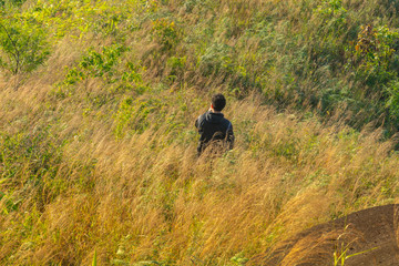 man walking through grass top of the mountain at Kanchanaburi, Thailand