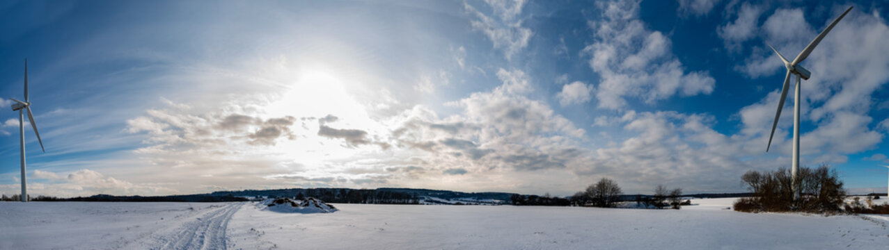 Panoramique avec des éoliennes d'un paysage en hiver avec de la neige sur fond de ciel bleu en Moselle