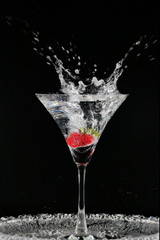 Cocktail with strawberries isolated on black background.Glass of vodka splashing.