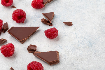 Dark chopping chocolate with fresh raspberries. Top view, copy space, white background.