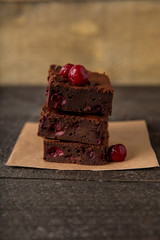 Brownie dessert slices with cherry on a plate, wooden background