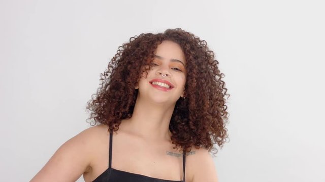 mixed race black woman with freckles and curly hair slowly dancing and touches her curly afro hair