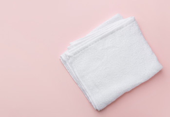 Folded clean white fluffy terry towel on pastel pink background. Minimalist flat lay. Women's baby hygiene laundry body care wellness well-being concept. Copy space