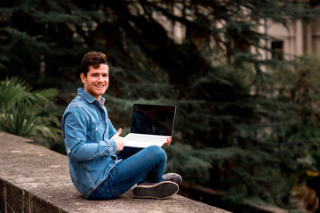 Obraz premium happy smiling Man in jeans suit sit with a laptop in garden