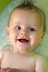 Portrait of a joyful baby who swims in the children's pool for infants in the summer.