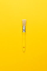 paint brush with yellow handle on the yellow background