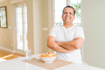 Middle age man eating rice at home happy face smiling with crossed arms looking at the camera. Positive person.