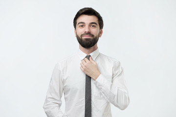 Man in shirt dressing up and adjusting tie on neck