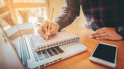 businessman hand working with new modern computer, tablet and writing on the notepad strategy diagram as concept morning light