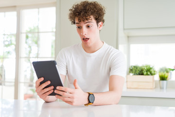 Young man using touchpad tablet scared in shock with a surprise face, afraid and excited with fear expression