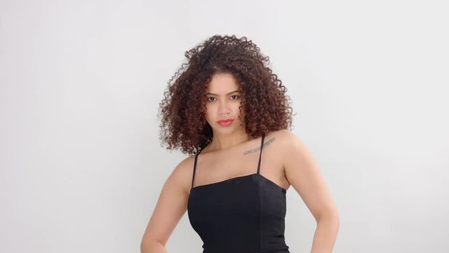 mixed race black woman with freckles and curly hair dancing moves her shoulders