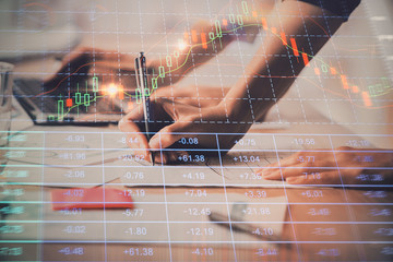 Close up of hands writing with double exposure of business charts. Financial concept.