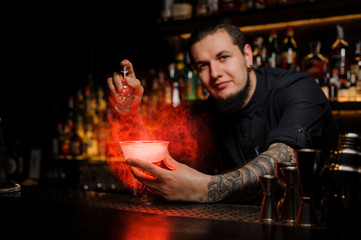 Smiling bartender spraying on the delicious cocktail from the vaporizer