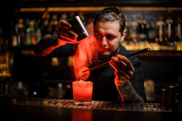 Bartender adding to a drink a dried orange and powder