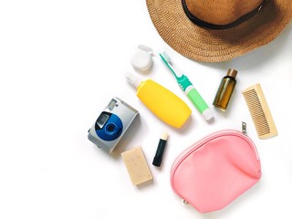 Flat lay photo sun hat, camera, yellow sunscreen lotion spray, toothbrush, dental floss, shampoo in small package, lips balm, soap bar and cosmetic bag. Travel cosmetics for hair, skin care 