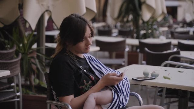 A young mother breastfeeding her little baby in the cafe