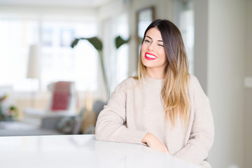 Young beautiful woman wearing winter sweater at home winking looking at the camera with sexy...