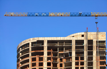 Facade and construction crane near the modern concrete building under construction.