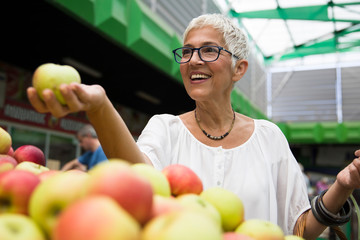 Senior woman buying apples on market