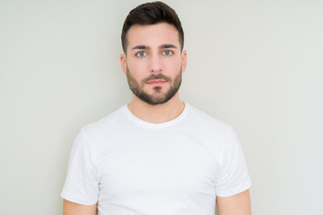 Fototapeta premium Young handsome man wearing casual white t-shirt over isolated background with serious expression on face. Simple and natural looking at the camera.