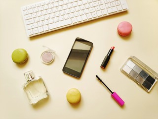 Flat lay photo white keyboard, macaroons cookies, smartphone, makeup products. Online order in...