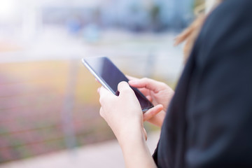 Executive working with a mobile phone in the street with office buildings in the background