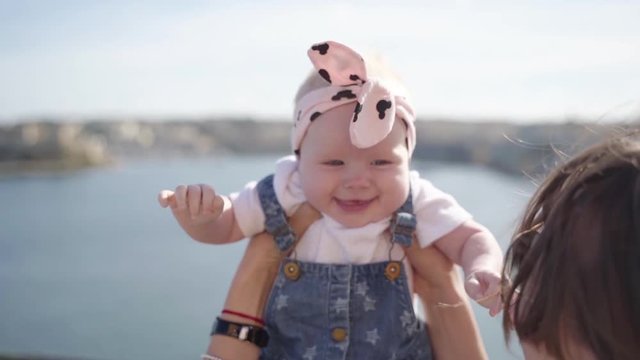 A close-up plan of a squinting from the sun baby and smiling to mother