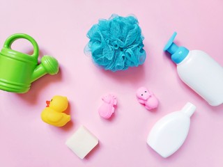 Flat lay still life baby cosmetics and rubber toys. Natural organic shampoo, liquid soap, yellow duck, hippo, sea horse on a pink background