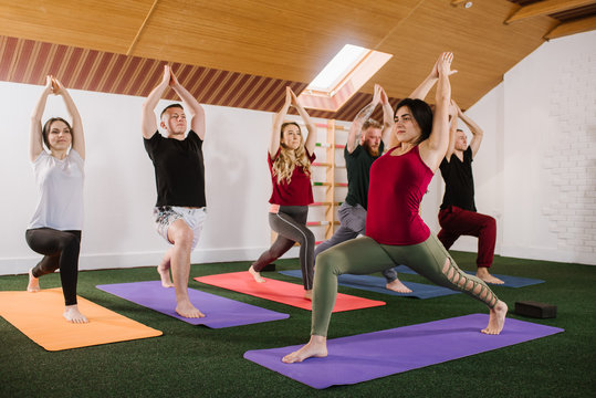 A group of a young people doing joga exercises indoors at the gym