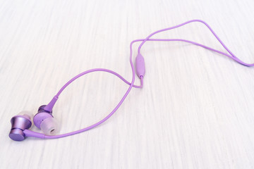 Purple earphones on wooden background