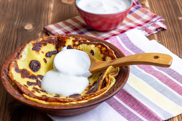 Pancakes with sour cream. Traditional Russian Shrovetide Maslenitsa festival meal on wooden background