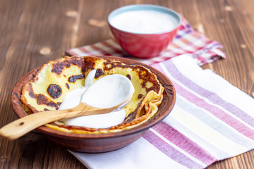 Pancakes with sour cream. Traditional Russian Shrovetide Maslenitsa festival meal on wooden background