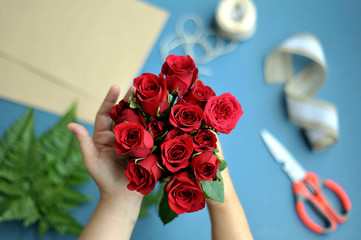 A woman hand holding a bunch of red roses to make a bouquet 