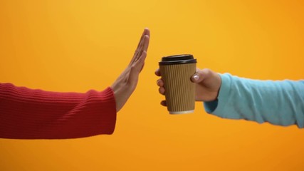 Female rejecting cup of coffee showing stop sign, health care, harmful drink