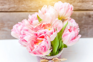 Spring greeting card. Bouquet of fresh light pastel pink tulips flowers on wooden background. Happy holiday easter mother day anniversary valentine day birthday concept. Flat lay top view copy space