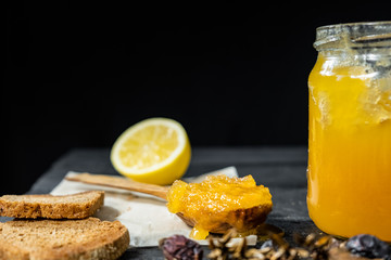 Spoonful of honey on dark rustic background. Crystallized home-made honey in jar, low-key shot