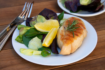Fresh salad with chicken grilled breast and lemons. top view, healthy food plate. Wooden table.
