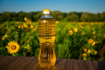 Bottle of oil on wooden stand with sunflowers field background. Sunflower oil improves skin health and promote cell regeneration