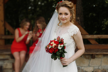 gorgeous bride smiling and posing with wedding bouquet outdoors with her bridesmaids. luxury wedding couple at reception at church yard. girls having fun