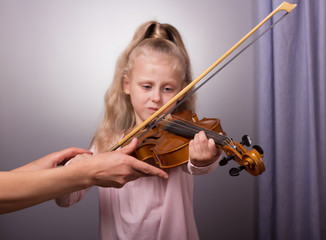 Learning to play the violin. Little girl tries to correctly hold the tool
