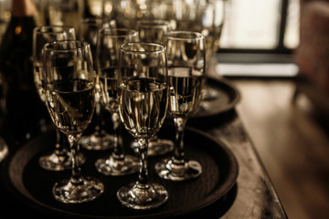 luxury glasses with golden champagne on stylish decorated table at wedding reception. expensive catering at restaurant for celebrations. transparent glass and space for text